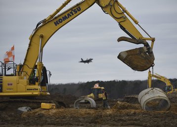 Aspen Construction workers move a segment of cement pipe on the airfield construction site at Joint Base Langley-Eustis, Virginia,