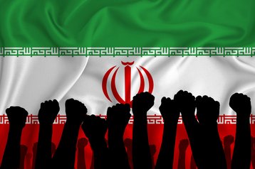 Silhouette of raised arms and clenched fists on the background of the flag of Iran.