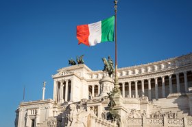 Bandera italiana con el rey Víctor Manuel II monumento ecuestre de fondo. Piazza Venezia, Roma, Italia.