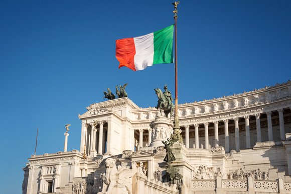 Bandera italiana con el rey Víctor Manuel II monumento ecuestre de fondo. Piazza Venezia, Roma, Italia.