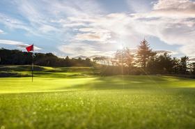Golf course putting green with flag at sunset