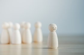 Bullying concept of wooden figures singling out one sad one