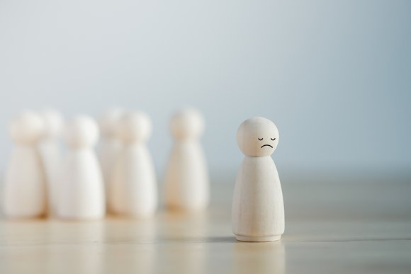 Bullying concept of wooden figures singling out one sad one