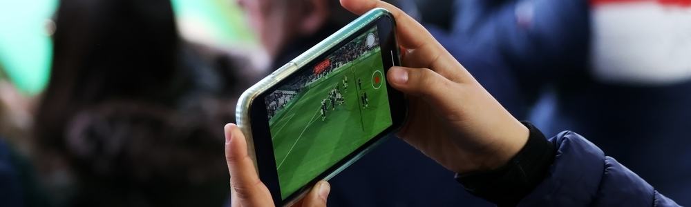 A fan recording a football match from the stands with his mobile phone