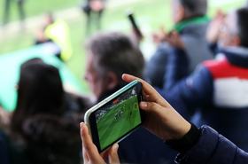 A fan recording a football match from the stands with his mobile phone