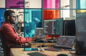 African American Man Writing Lines Of Code On Desktop Computer With Multiple Monitors and Laptop in Creative Office. Male Data Scientist Working on Innovative Online Service For Start-up Company. Hombre. Homem. Cyber. Ciber