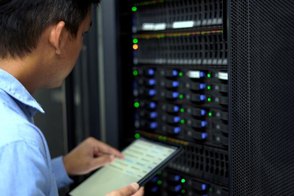 IT technician inspects and manages a server rack in a data center