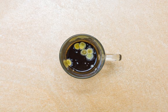 A mug of coffee with mould in it