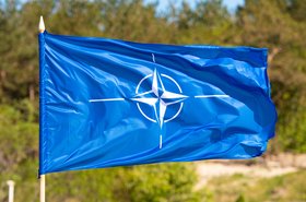 lag with symbol of NATO waiving on a blurred green background