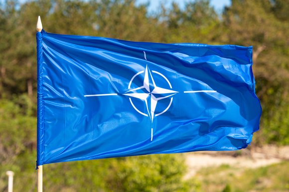 lag with symbol of NATO waiving on a blurred green background