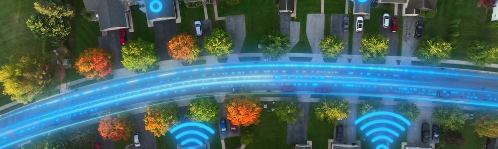 Aerial top-down view of American homes with glowing fiber optic lines and Wi-Fi symbols showing high-speed internet