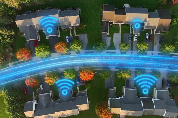 Aerial top-down view of American homes with glowing fiber optic lines and Wi-Fi symbols showing high-speed internet