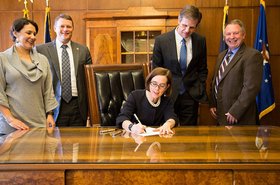Gov. Kate Brown (center) signs Senate Bill 611 into law